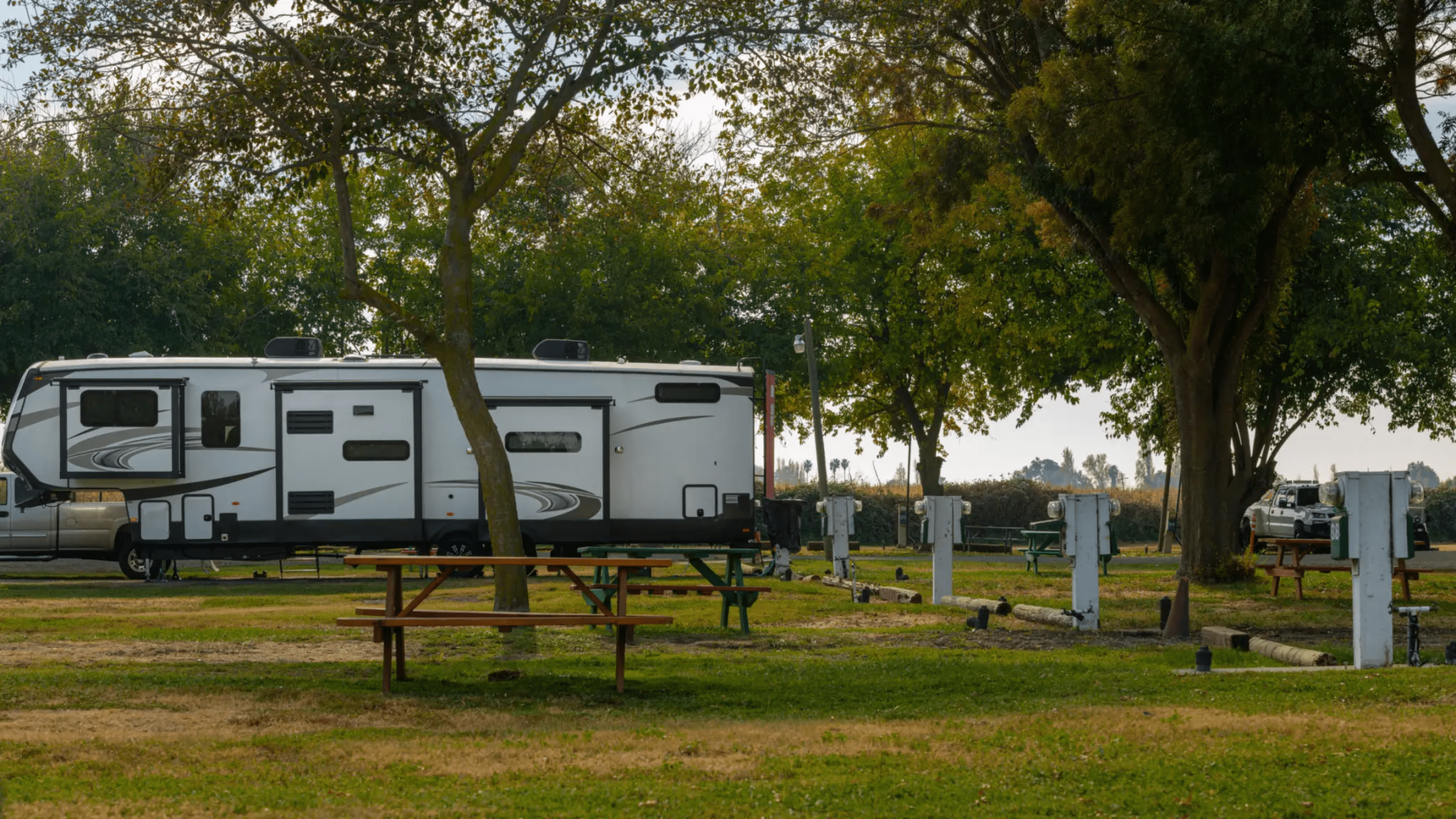 Studio-Project A white trailer parked in the grass near some trees.